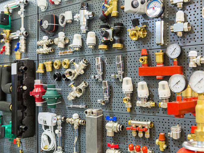Various plumbing fittins on a pegboard in a plumbing supply store